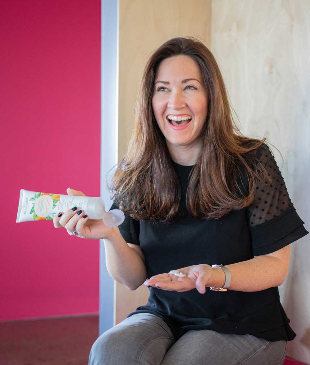 Femme riant en appliquant sur sa main la crème pour le corps énergisante Super Leaves ATTITUDE_fr?_hover? ALL_VARIANTS