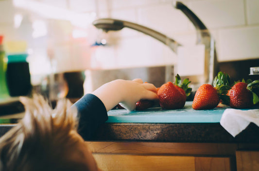 Enfant dans la cuisine attrapant un fruit.|